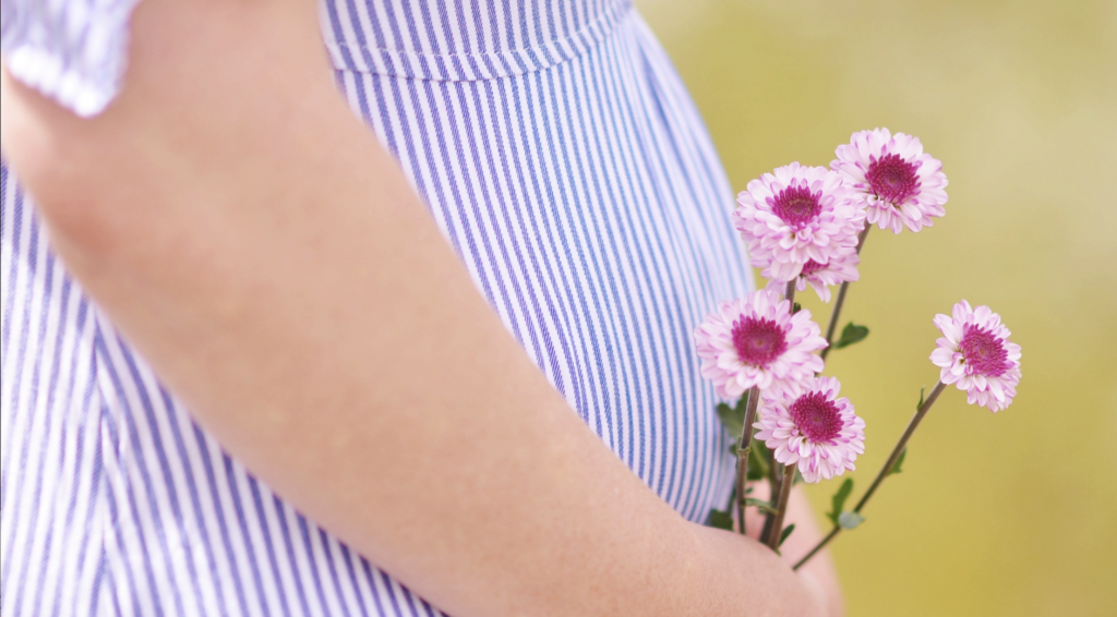 You feel exhausted. And nauseous. But does that mean you're pregnant? Here are five sure signs of pregnancy. Photo of a pregnant belly in a blue dress holding pink flowers, courtesy of Ashton Mullins