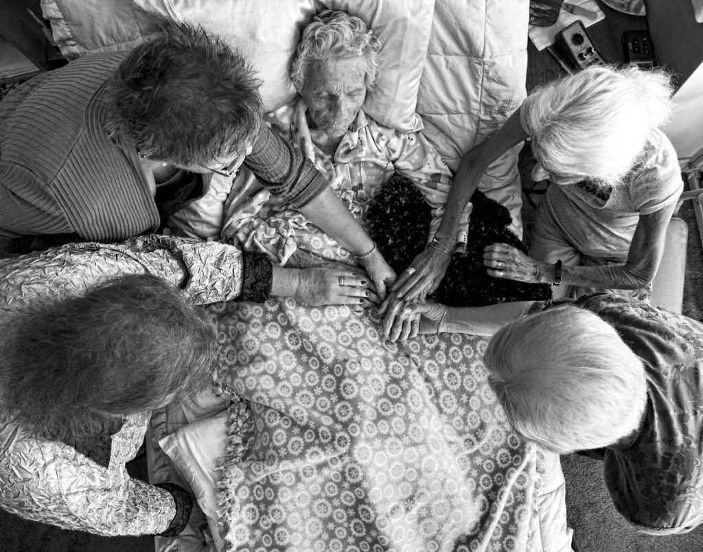 Dying comfortably surrounded by loved ones is a death with dignity. But how do we make sure that's what happens? Photo of a dying woman with her friends courtesy of Mary Landberg.