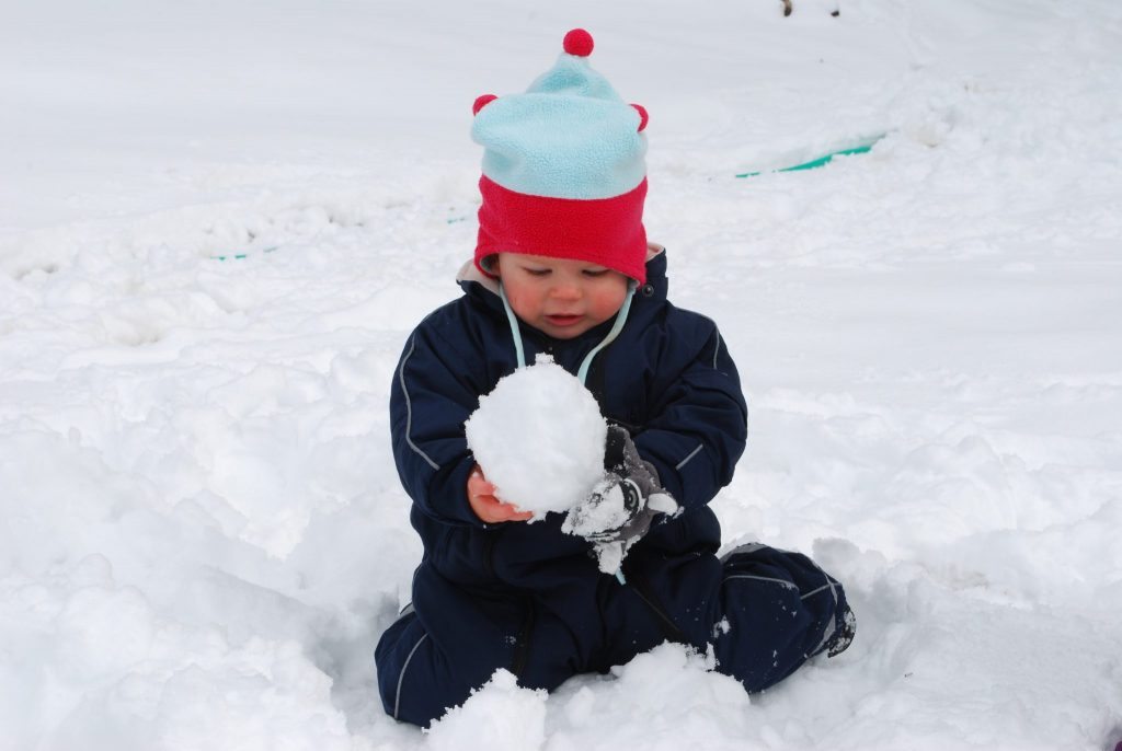A toddler plays in the snow. When hurry becomes a habit, everyone is unhappy. Stop rushing. Let them play. Photo by Lora Horvath
