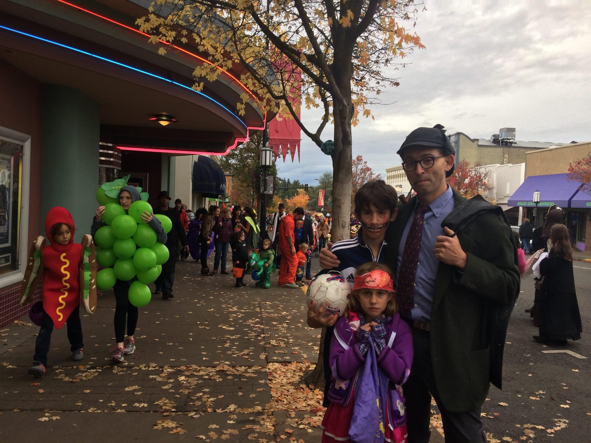 Mr. Sherlock Holmes accompanied by a zombie soccer player and a princess outside the Varsity Theater on Halloween in Ashland, Oregon