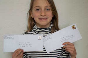 Holding up the donation envelopes before she mailed them. Instead of gifts, she asked friends to bring charitable contributions. We had an amazing green birthday party for her 8th birthday. | Jennifer Margulis
