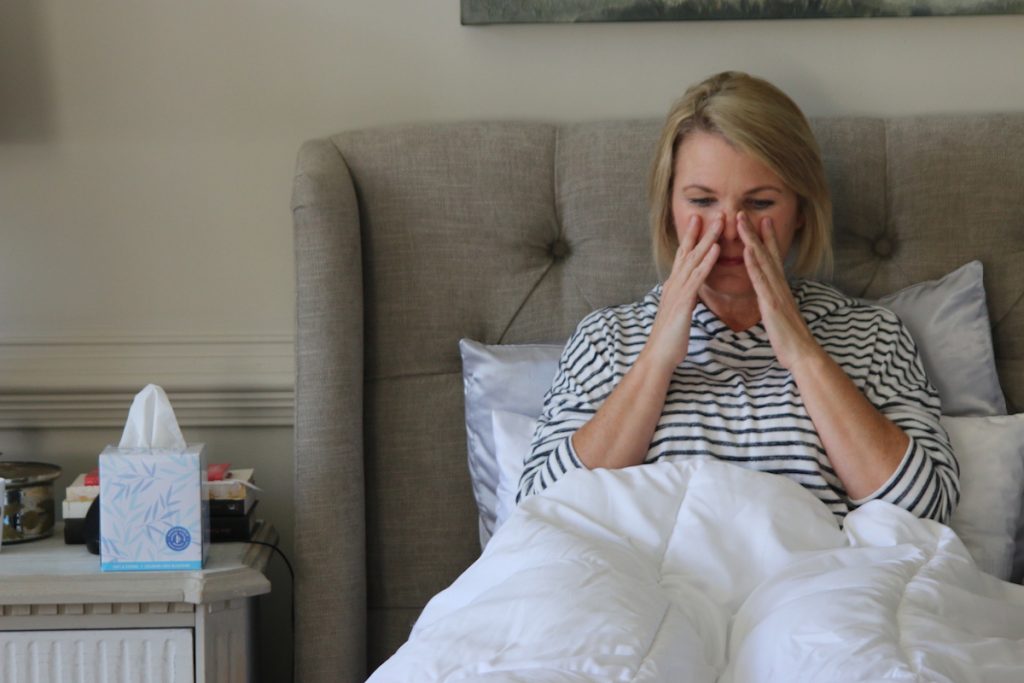 Treating a sinus infection without antibiotics, natural remedies that work. Photo of a sick woman in bed by Nicole Johnson. | Jennifer Margulis