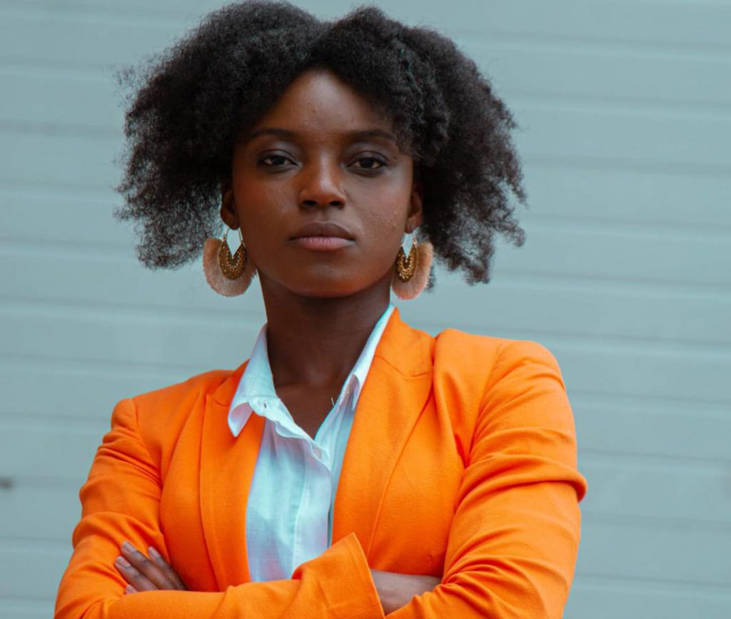 Scientific debate is needed during a pandemic. Photo of an African-American woman wearing an orange blazer via Unsplash. | Jennifer Margulis, Ph.D.